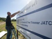 Mike Kiessling, director of the Northwest Line Construction Industry's Joint Apprenticeship Training Committee, installs a sign on the training program's new property at 1705 S.E. 17th St. in  Battle Ground.