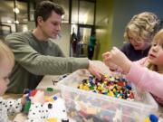 The Collmer family, from left, Vivian, 2, Chris, Sarah, and Lucy, 4, play with LEGOs at the new Vancouver Community Library on Tuesday.