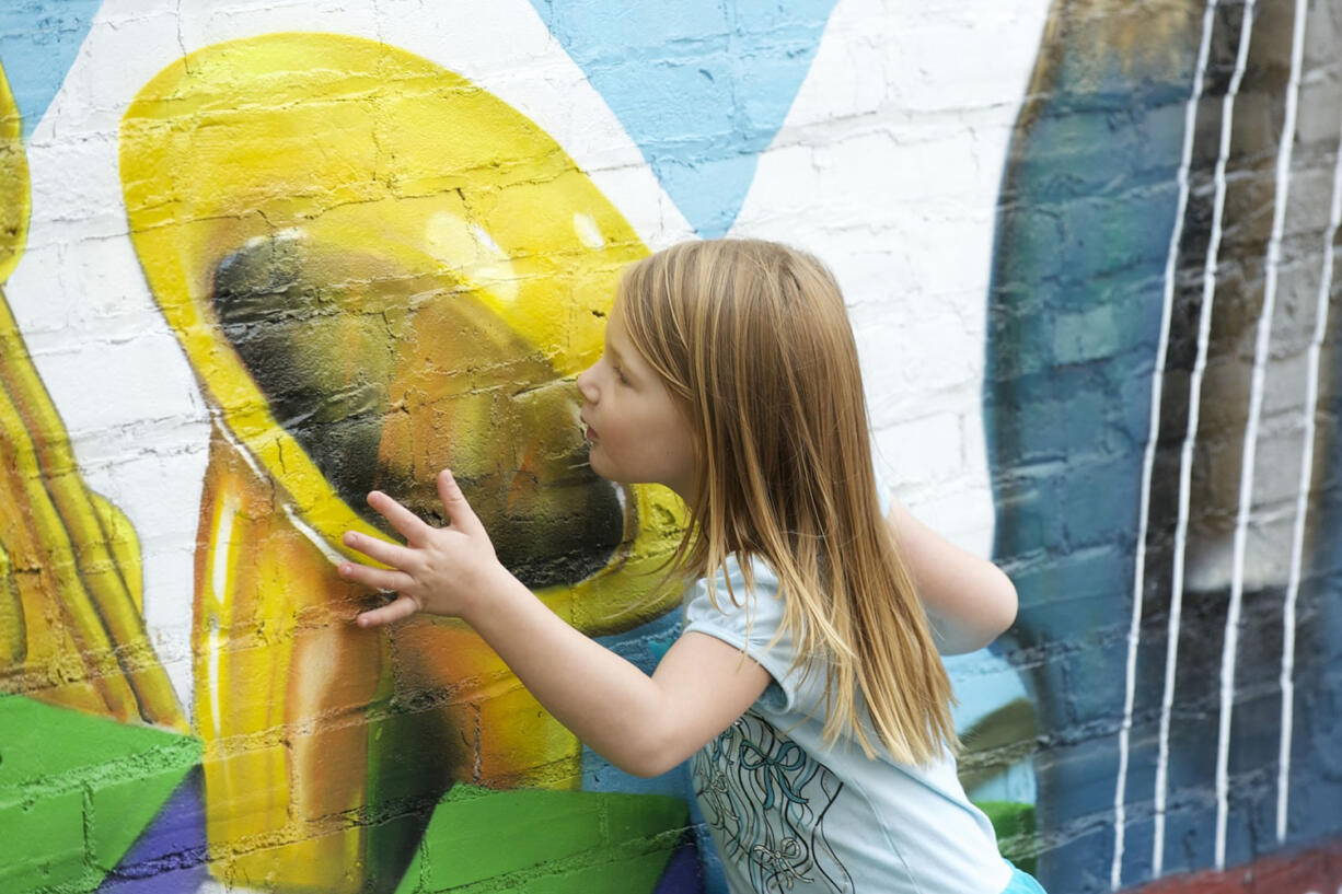 Poppy Lindberg, 4, of Vancouver &quot;listens&quot; to a mural on the exterior wall of Briz Loan and Guitar, 506 Washington St., during a walking tour of murals hosted by Vancouver's Destination Downtown.