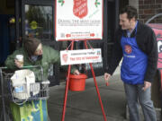 Volunteer bell ringer Tim Leavitt -- who moonlights as Vancouver mayor when he's not wearing that apron -- looks happy but chilly while thanking Dorothy Parkin for her donation during the first day of the Salvation Army's Red Kettle campaign.