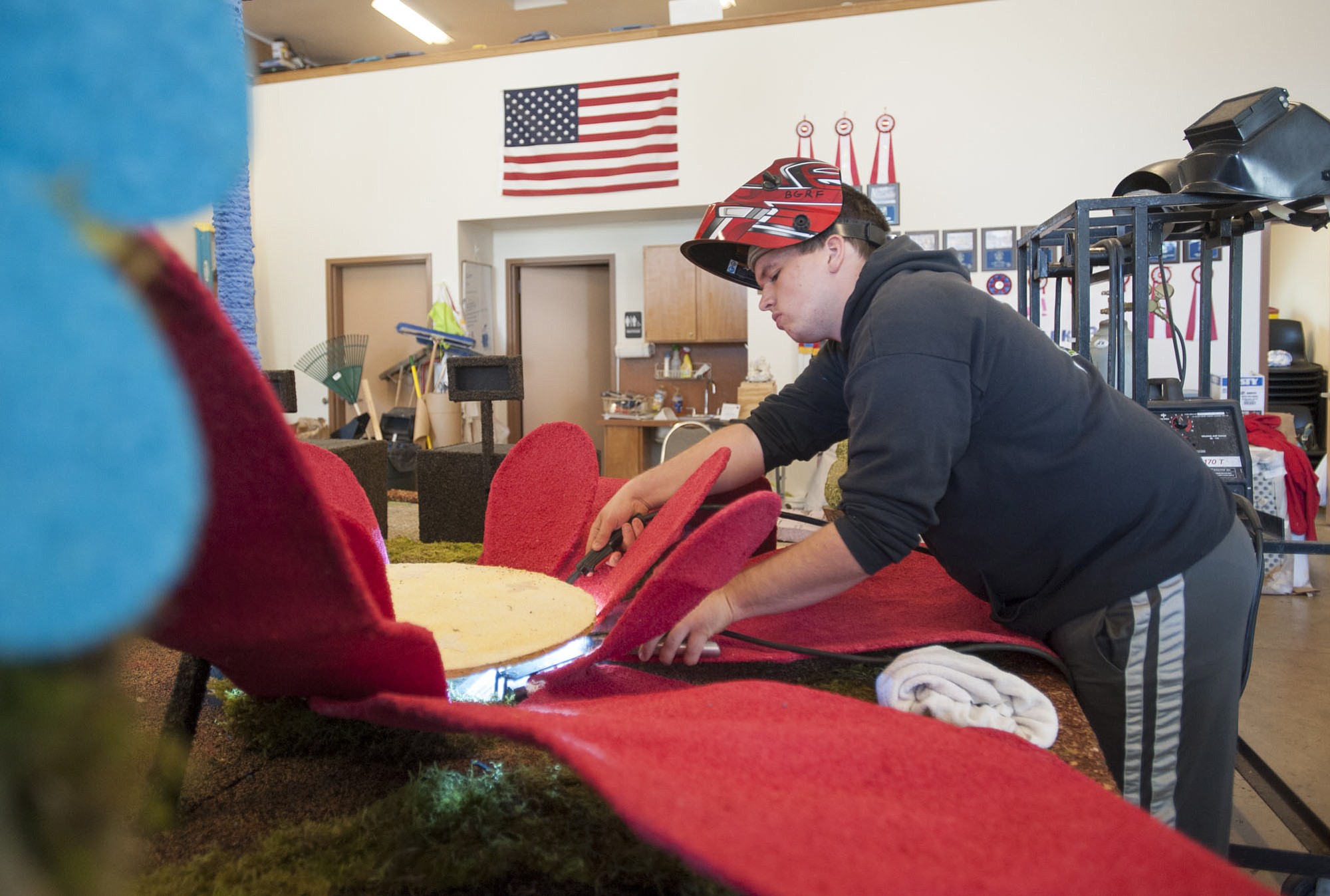 Austin Alling welds a flower petal to a stem on the Battle Ground parade float.