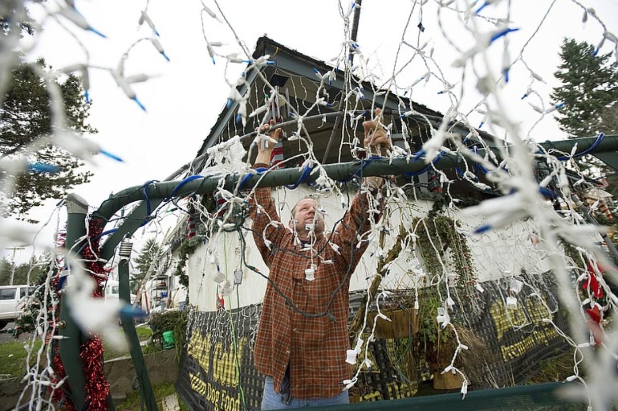 Bryan Miller removes Christmas lights from his yard in La Center last week.