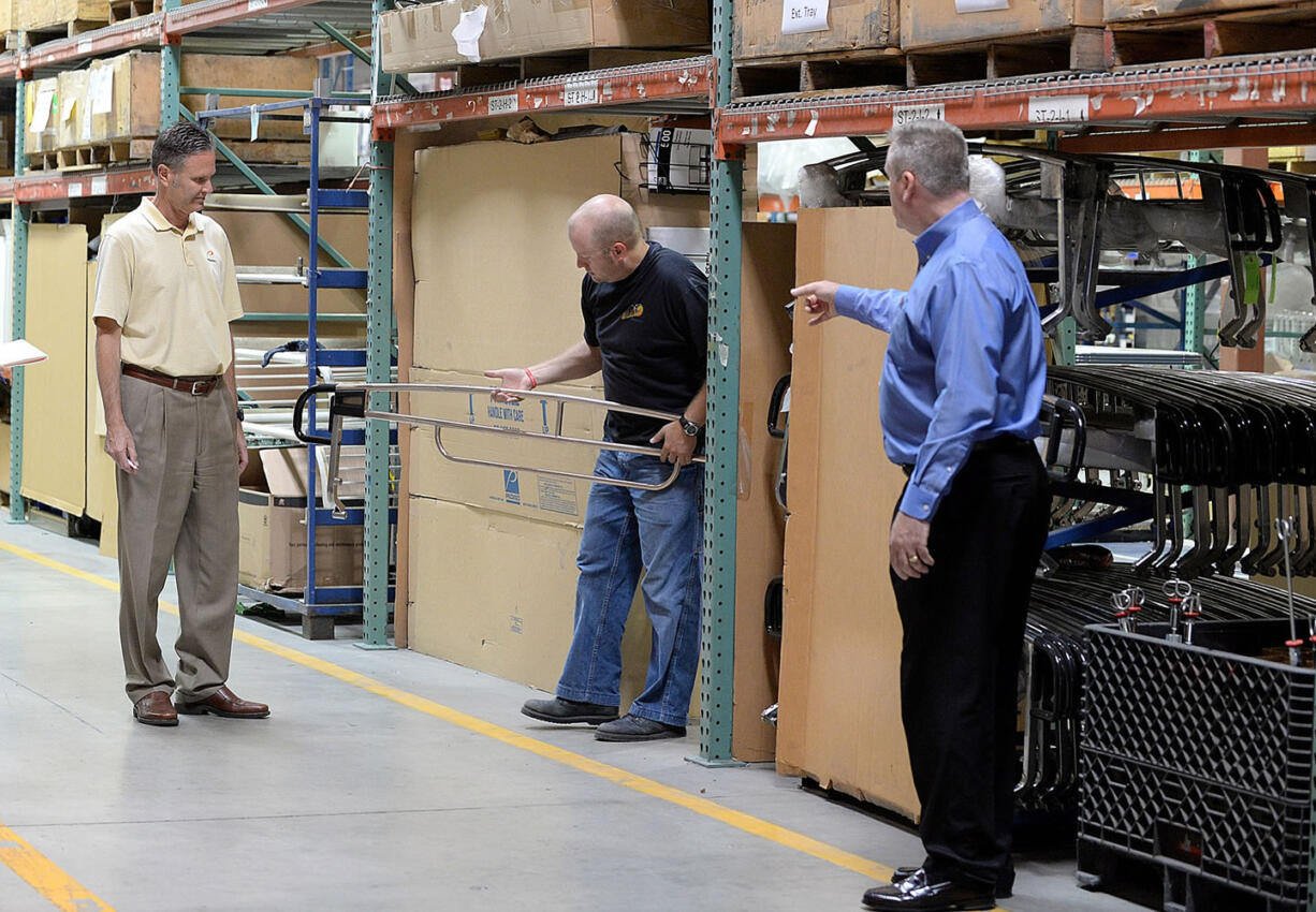 Neal Bradshaw, a manufacturing engineer at Pedigo Products, center, holds a copper handrail for a hospital stretcher as Rick Pedigo, chief executive officer, left, and Eric Hjort, director of business development, discuss the new product at the company's headquarters in Vancouver.