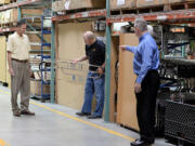 Neal Bradshaw, a manufacturing engineer at Pedigo Products, center, holds a copper handrail for a hospital stretcher as Rick Pedigo, chief executive officer, left, and Eric Hjort, director of business development, discuss the new product at the company's headquarters in Vancouver.