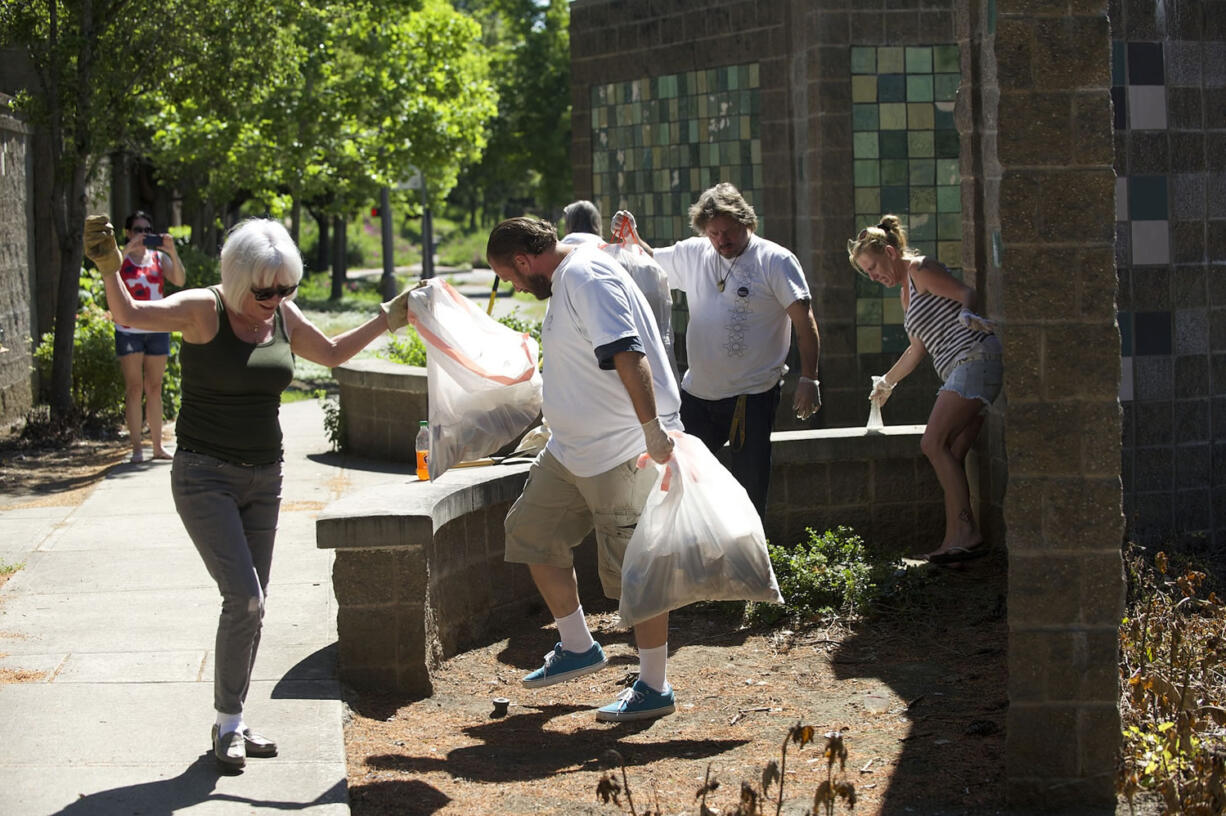 Share House residents and Hough neighbors work together to clean up the mess along the Mill Plain sound wall between Columbia and Lincoln streets on Tuesday.