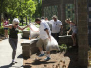 Share House residents and Hough neighbors work together to clean up the mess along the Mill Plain sound wall between Columbia and Lincoln streets on Tuesday.