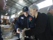 Air Force veteran Mike Burton, center, and Columbia River High School senior Isabel Kalnin package rice Tuesday at the Clark County Food Bank in Vancouver.