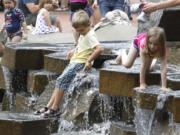 Children take advantage of a warm, muggy Saturday afternoon to enjoy the water feature at Vancouver's Esther Short Park.