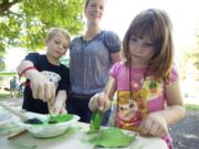 Photos by Steven Lane/The Columbian
Kevin Sheehan, 8, left, and sister Caoimhe Sheehan, 7, make leaf prints Wednesday at the Water Resources Education Center tent during the first Noon Concert at Esther Short Park in Vancouver.