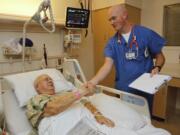 Registered nurse Jon Shinn visits with patient William C. Michael at Legacy Salmon Creek Medical Center. Shinn served in the U.S. Army Band Pershing's Own for six years, playing for more than 1,000 soldiers' funerals, before deciding to become a nurse.