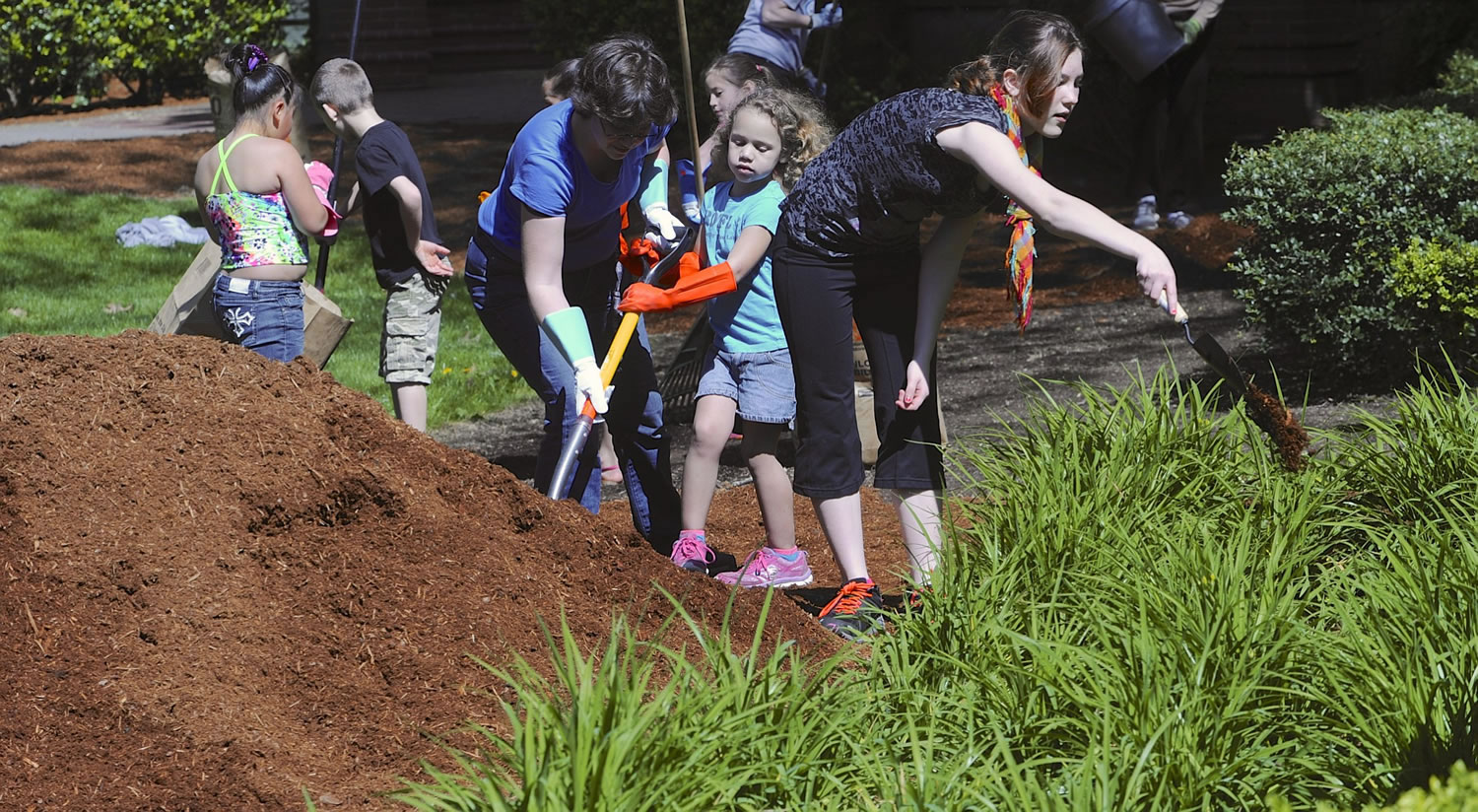 Cherakee Elliott, right, works by spreading bark dust Saturday as volunteers from a number of organizations, including Share House Open House Ministries and Umpqua Bank clean up Esther Short Park in Vancouver.