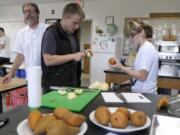 CASEE students Jeramiah Young, in black vest, and MacKenzie Graham peel bosc pears grown in CASEE's orchard.