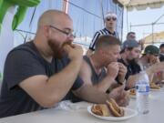 Chris Munoz of Vancouver, left, finishes his eighth hot dog Sunday afternoon during a hot dog eating contest at the Clark County Fair. Munoz won the competition.