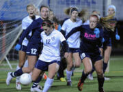 Olympia High School's Brooklyn Hooper (18) ) defends a clearance by Skyview's Sydnee Smith (12) in a girls' 4A state soccer playoff game at Kiggins Bowl on Wednesday Nov. 12, 2014. Olympia won on penalty kicks.