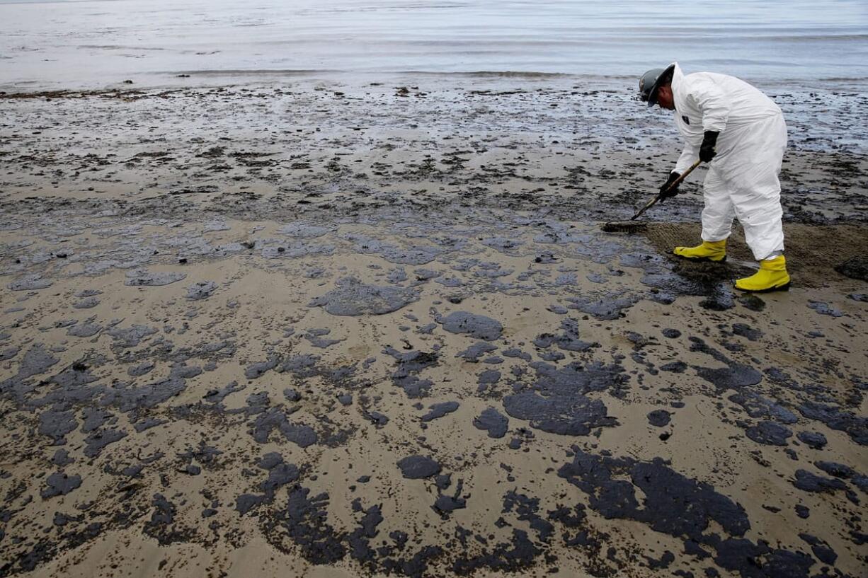 A worker removes oil from the beach Thursday at Refugio State Beach, north of Goleta, Calif.