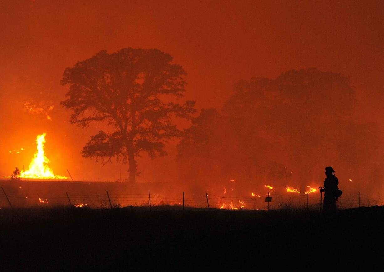 A firefighter watches a backfire as the Rocky Fire burns near Clearlake, Calif., on Monday.