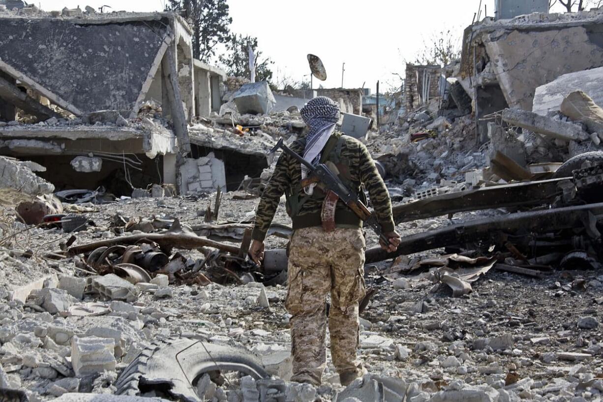 jake simkin/Associated Press files
A Kurdish People's Protection Unit (YPG) fighter walks through rubble of Kobani, Syria, on Nov. 19.