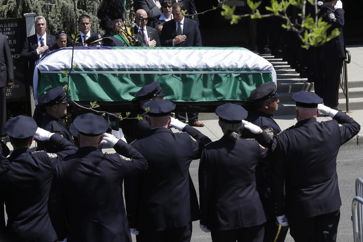 Police officers salute Friday as the casket carrying the remains of New York Police Department Officer Brian Moore arrives for his funeral Mass at the St. James Roman Catholic Church in Seaford, N.Y. The 25-year-old died Monday, two days after he was shot in Queens, while on patrol.