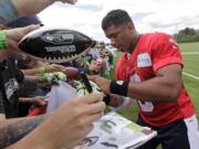 Seattle Seahawks quarterback Russell Wilson signs autographs following an NFL football camp practice Friday, July 25, 2014, in Renton, Wash.