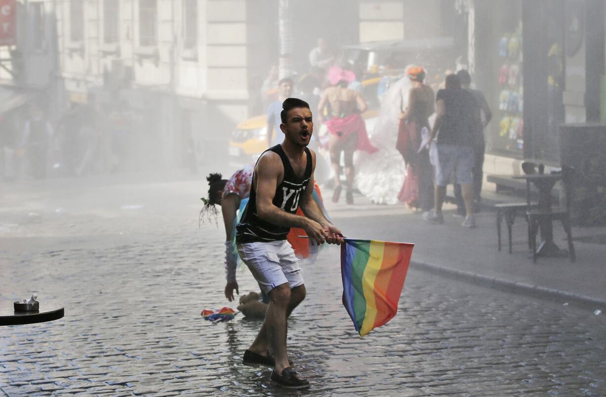 A participant in the Gay Pride event reacts Sunday as others flee after Turkish police use a water canon to disperse them in Istanbul, Turkey.