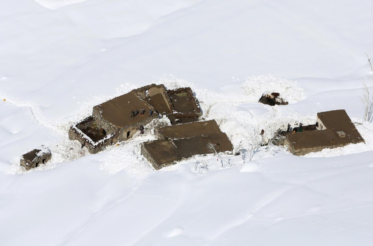 Afghans stand on their rooftops after an avalanche in the Paryan district of Panjshir province, north of Kabul, Afghanistan, Friday, Feb. 27, 2015. The death toll from severe weather that caused avalanches and flooding across much of Afghanistan has jumped to more than 200 people, and the number is expected to climb with cold weather and difficult conditions hampering rescue efforts, relief workers and U.N. officials said Friday.