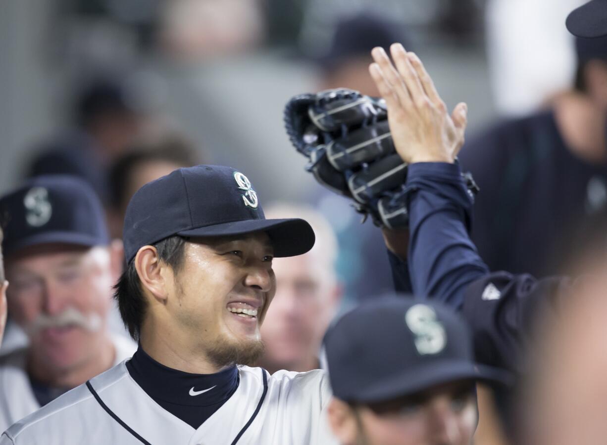 Seattle Mariners starter Hisashi Iwakuma is congratulated in the dugout by teammates during the eighth inning.