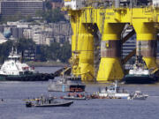 A small flotilla of kayakers and other protest boats follow as the oil drilling rig Polar Pioneer is towed toward a dock Thursday, May 14, 2015, in Elliott Bay in Seattle. The rig is the first of two drilling rigs Royal Dutch Shell is outfitting for oil exploration and was towed to the Port of Seattle site despite the city's warning that it lacks permits and threats by kayaking environmentalists to paddle out in protest.