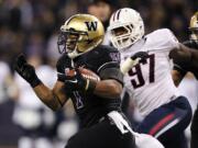 Washington's Chris Polk, left, is chased by Arizona's Mohammed Usman during the first half Saturday.