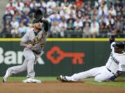 Oakland Athletics third baseman Brett Lawrie reaches to catch the pick-off throw as Seattle Mariners' Robinson Cano, right, attempts to steal second base in the second inning Monday, Aug. 24, 2015, in Seattle. Lawrie's tag on Cano was ruled an out after the initial safe call on the field was challenged by the Athletics. (AP Photo/Ted S.