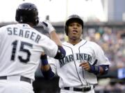 Seattle Mariners' Robinson Cano, right, is congratulated by Kyle Seager after scoring against the Oakland Athletics on Saturday, May 9, 2015, in Seattle.