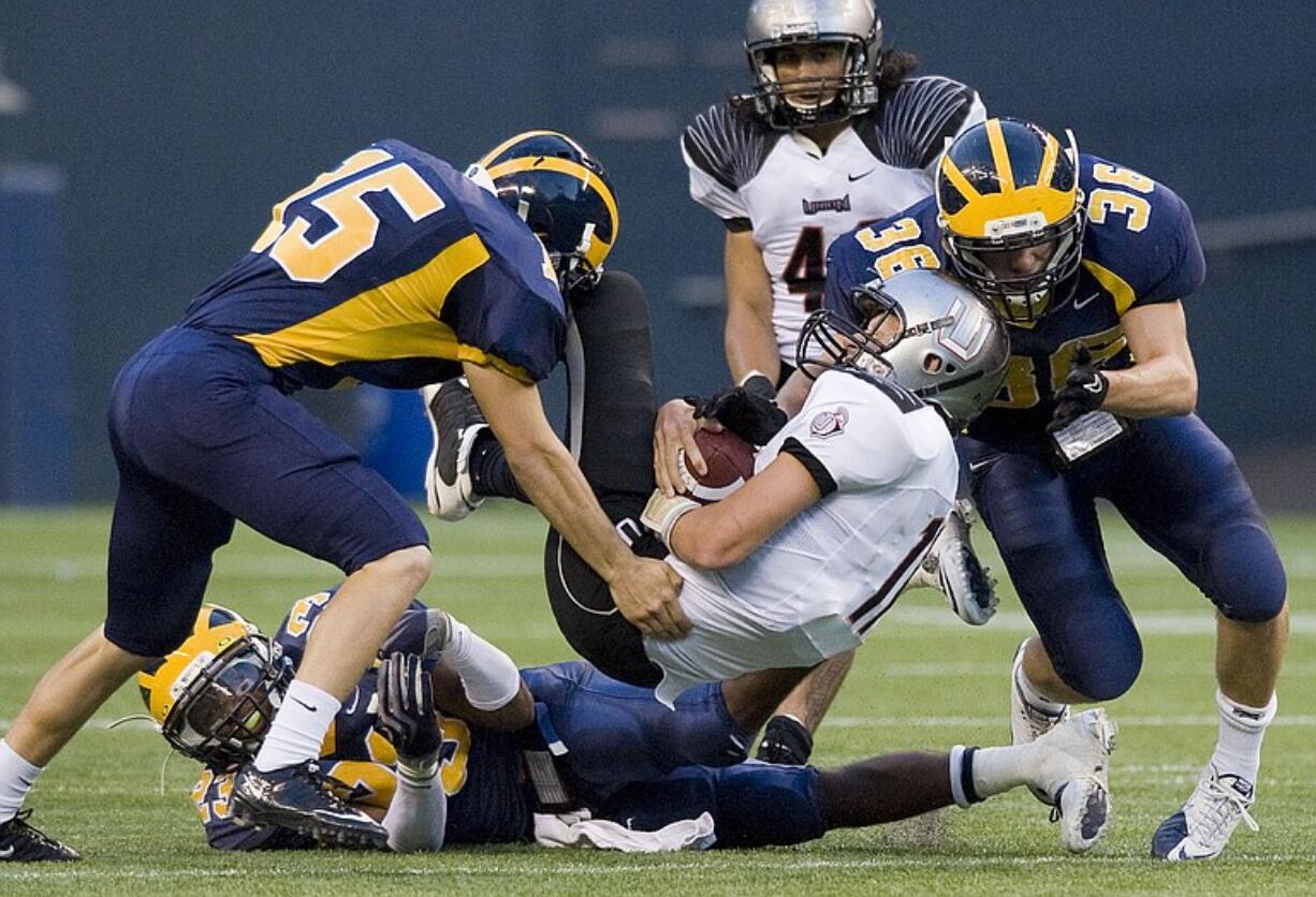 Union quarterback Tanner Nelson is stopped by Bellevue's Matt Gilbert, left, and William Bissell, #36,