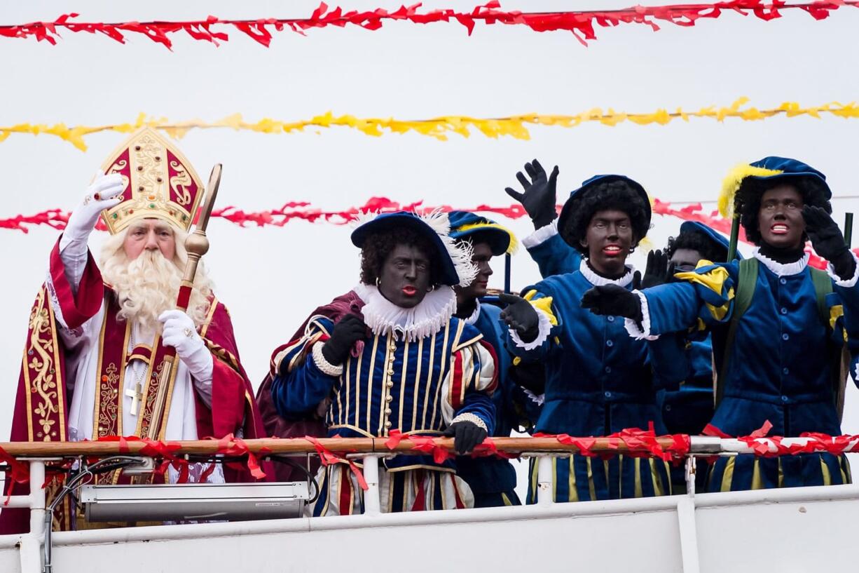 White actors dressed as St. Nicholas, left, and his sidekick Black Pete arrive Saturday on a boat in Antwerp, Belgium.