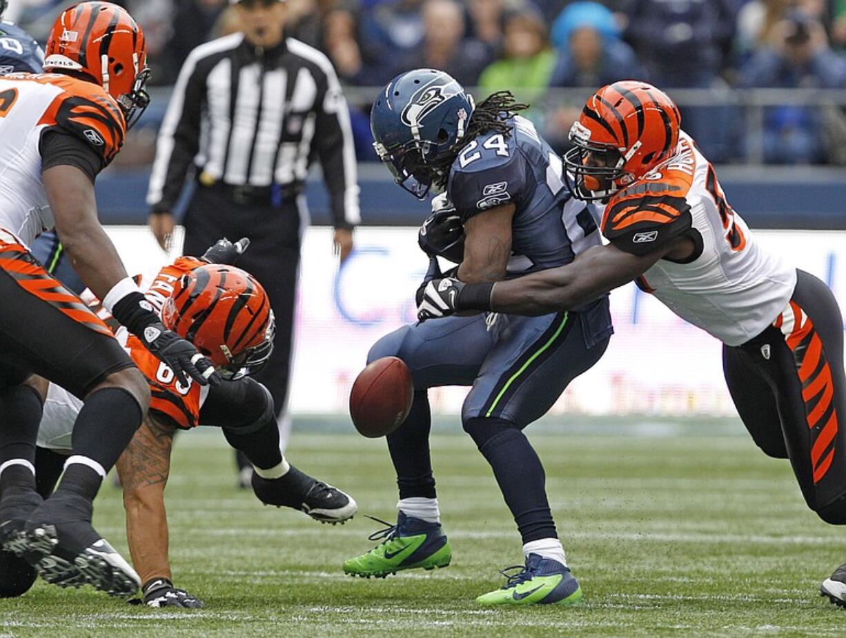 Seattle Seahawks' Marshawn Lynch (24) has the ball stripped by Cincinnati Bengals' Dontay Moch during the first half Sunday.