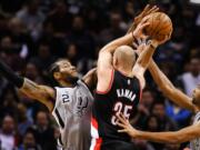 San Antonio Spurs forwards Kawhi Leonard, left, and Tim Duncan, right, defend against Portland Trail Blazers center Chris Kaman in the second half Friday, Jan. 16, 2015, in San Antonio. The Spurs won 110-96.