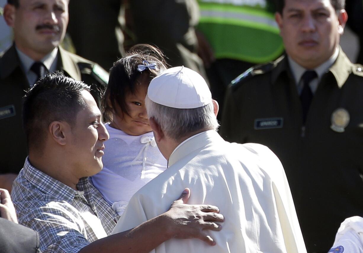 Pope Francis greets a man and child Friday inside Palmasola prison in Santa Cruz, Bolivia. The pope urged inmates at the notoriously violent prison to not despair as he wrapped up his visit to Bolivia with a message of hope and solidarity for those caught up in Bolivia's corrupt law enforcement system.