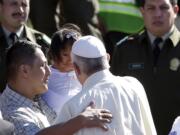 Pope Francis greets a man and child Friday inside Palmasola prison in Santa Cruz, Bolivia. The pope urged inmates at the notoriously violent prison to not despair as he wrapped up his visit to Bolivia with a message of hope and solidarity for those caught up in Bolivia's corrupt law enforcement system.