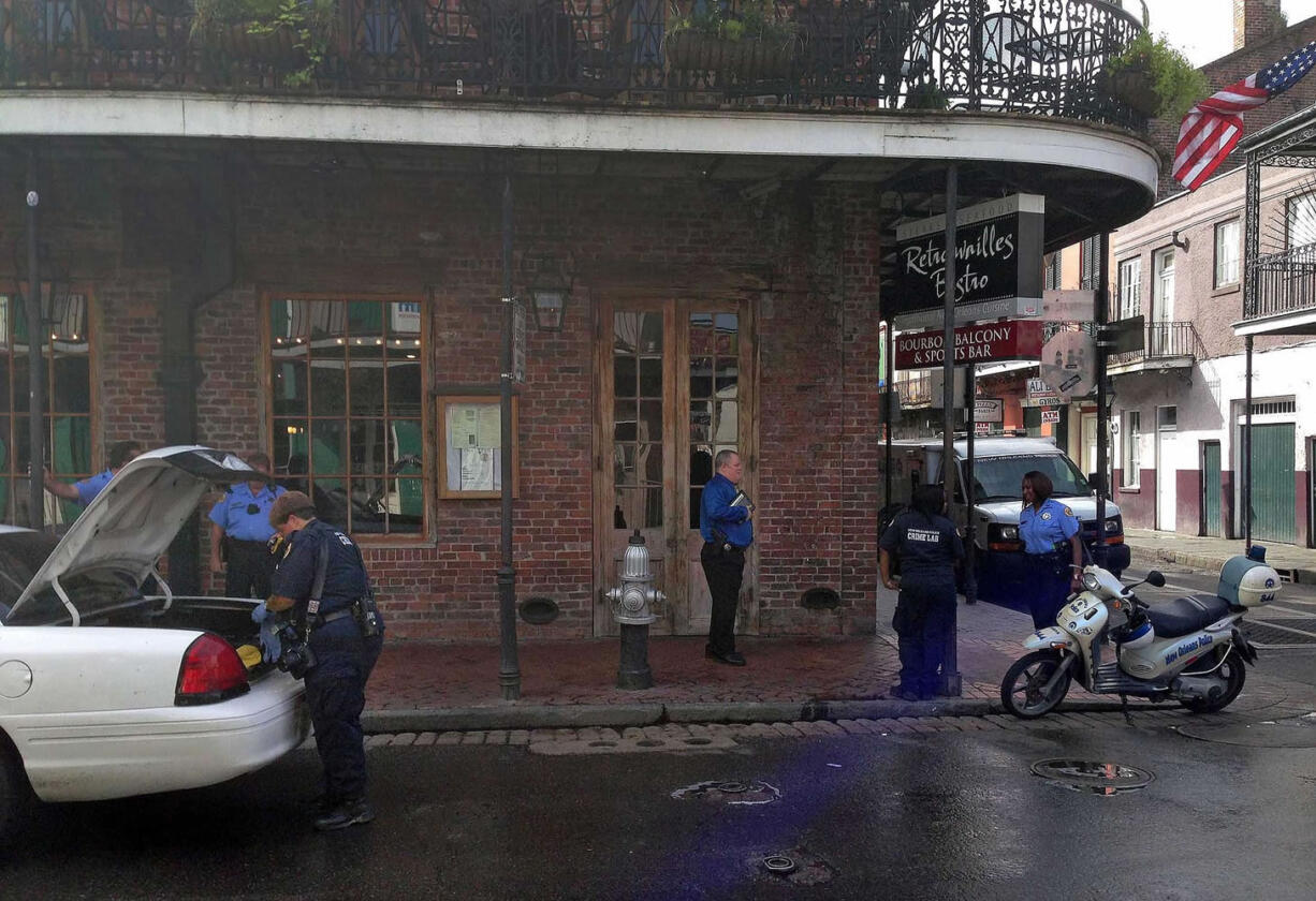 After a shooting on Bourbon Street, an apparent gunshot hole is seen in a door of the Bourbon Heat night club, as one employee sweeps up the sidewalk outside, early Sunday in New Orleans.