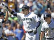 Seattle Mariners' Logan Morrison, center, is congratulated by Chris Taylor, left, and followed by Kyle Seager on Morrison's three-run home run against the Atlanta Braves in the third inning of a baseball game Wednesday, Aug. 6, 2014, in Seattle.