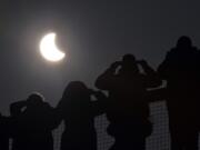 People watch as a solar eclipse begins over the Eden Project near St.