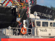 The Coast Guard stands by as a woman identified as Chiara D?Angelo has suspended herself Friday in a climbing harness from the anchor chain of the Royal Dutch Shell support ship Arctic Challenger in the harbor at Bellingham.