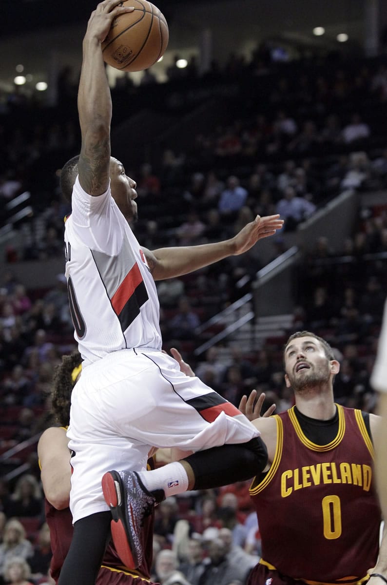 Portland guard Damian Lillard, left, goes to the basket over Cleveland Cavaliers forward Kevin Love, right, during the second half in Portland on Tuesday.