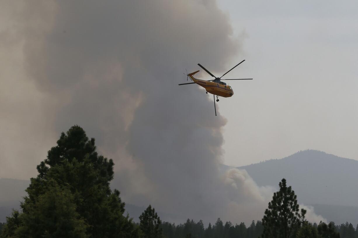 A helicopter flies toward the Two Bulls Fire west of Bend, Ore., on Sunday.