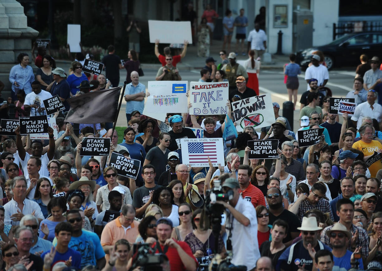 Protesters holds signs during a rally to take down the Confederate flag at the South Carolina Statehouse on Saturday  in Columbia, S.C. Rep.