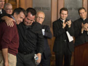 Abuse survivors Al Michaud, left, and Jim Keenan embrace after they both spoke of the importance of this historic agreement as attorney Jeff Anderson, Bishop Andrew Cozzens and Vicar General Rev. Charles Lachowitzer at right look on in St. Paul, Minn., Monday, Oct. 13, 2014. A Minnesota judge signed off on a settlement in a groundbreaking case that accused Catholic church leaders in Minnesota of creating a public nuisance by failing to warn parishioners about an abusive priest.