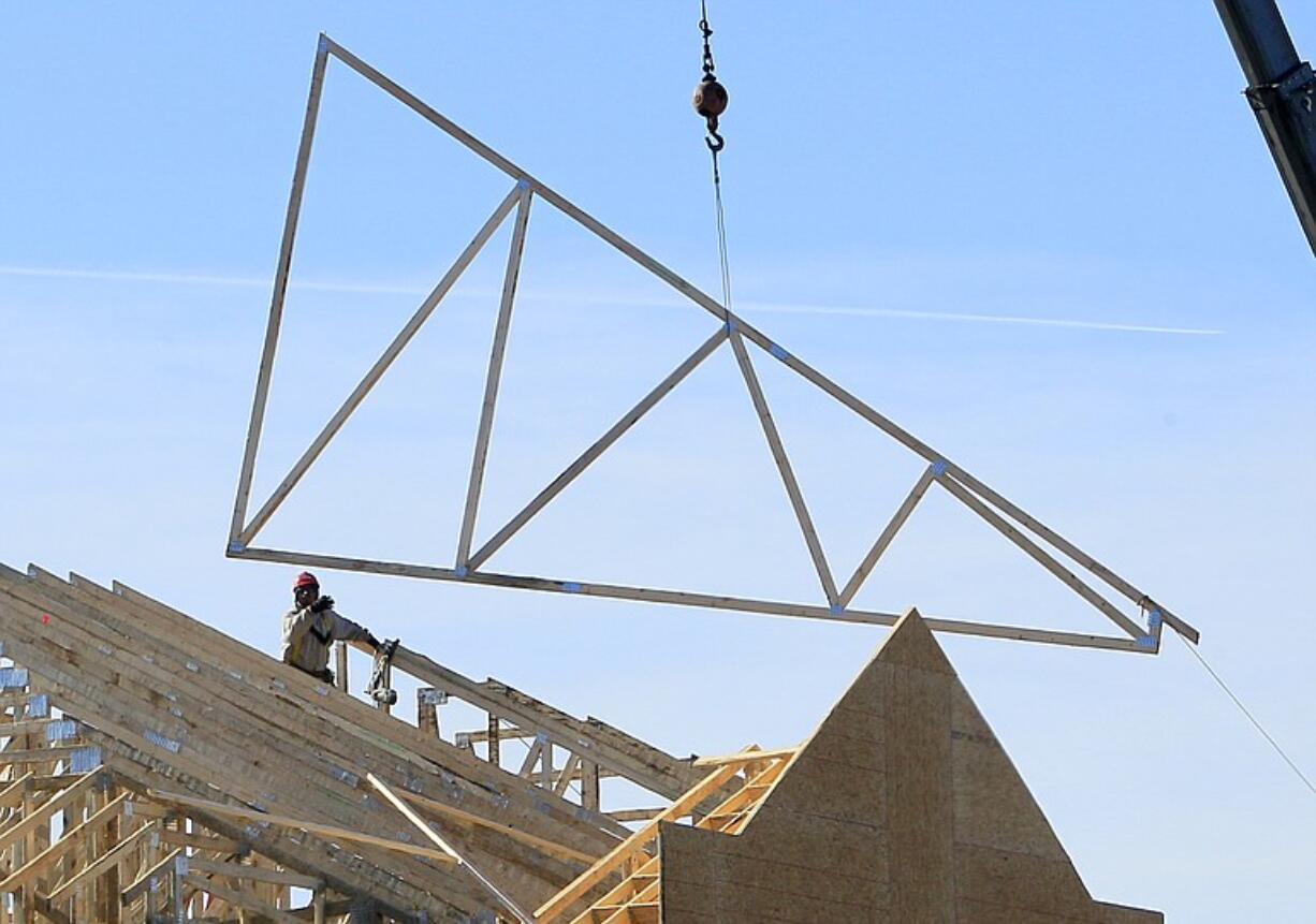 A construction worker guides a truss into position at a construction site Thursday in Dayton, Ohio.