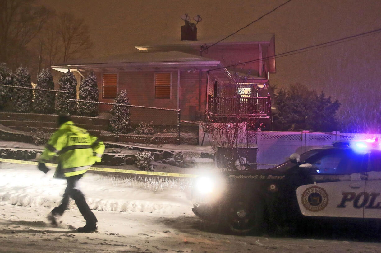 A Harrison police officer stands outside a house where the bodies of a retired police officer and two of his daughters were found Saturday in Harrison, N.Y.