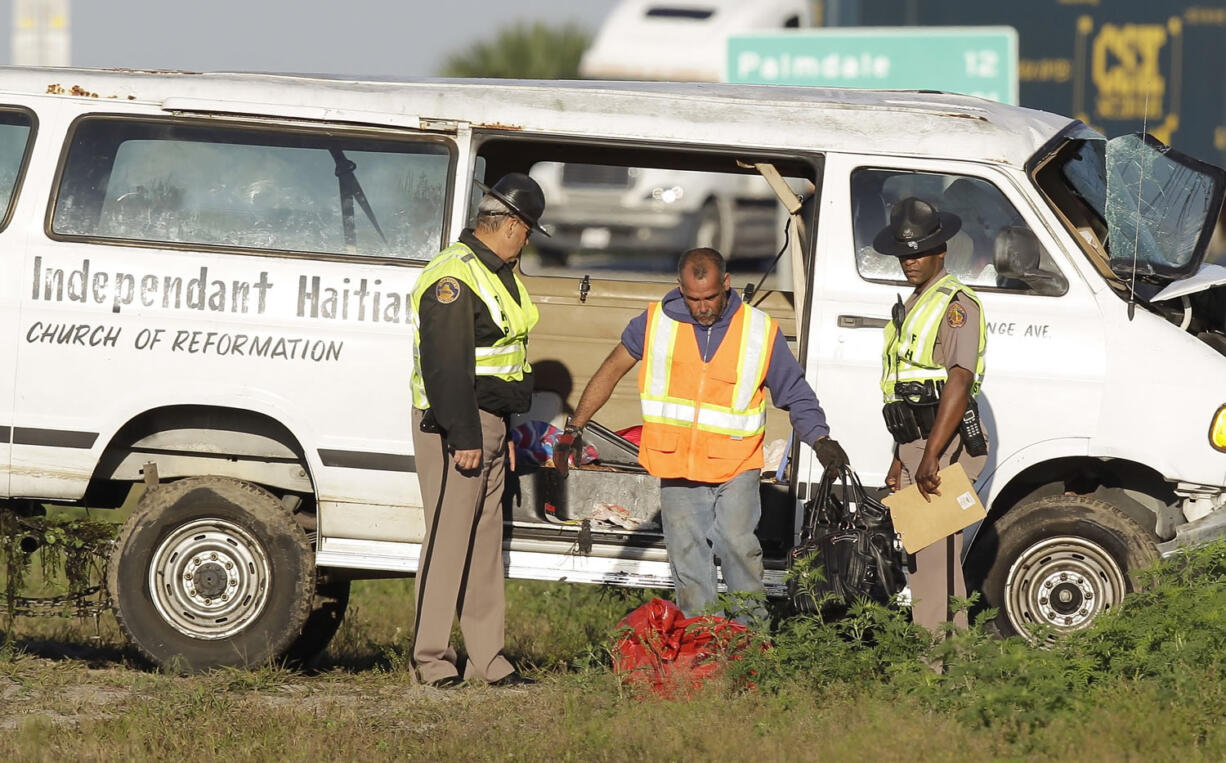 A worker, center, removes purses from van after it was removed from a canal at the intersection of US 27 and State Road 78 West on Monday near Moore Haven, Fla.