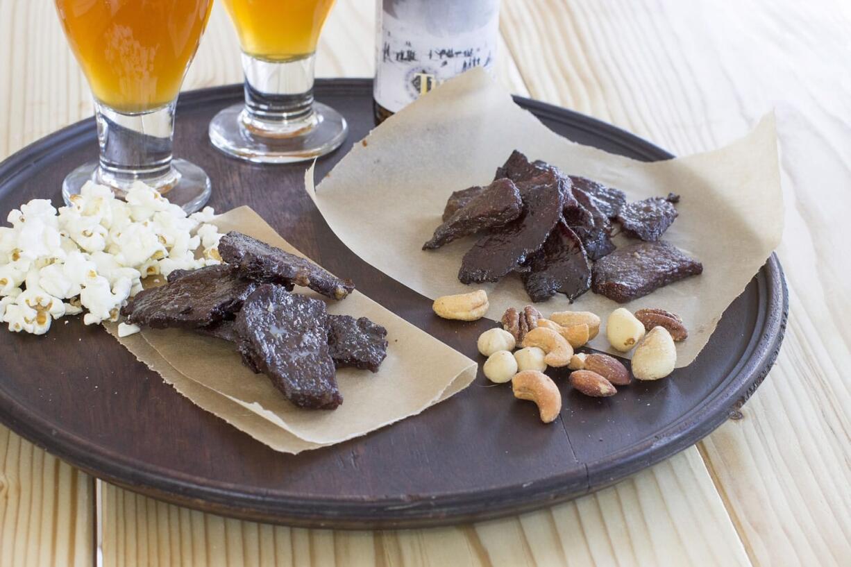 MatthewMead/Associated Press
Seasoning and drying your own meat is a simple process that requires little hands on time. Maple coffee pepper jerky, left, and sweet heat beef jerky are ready for game day.