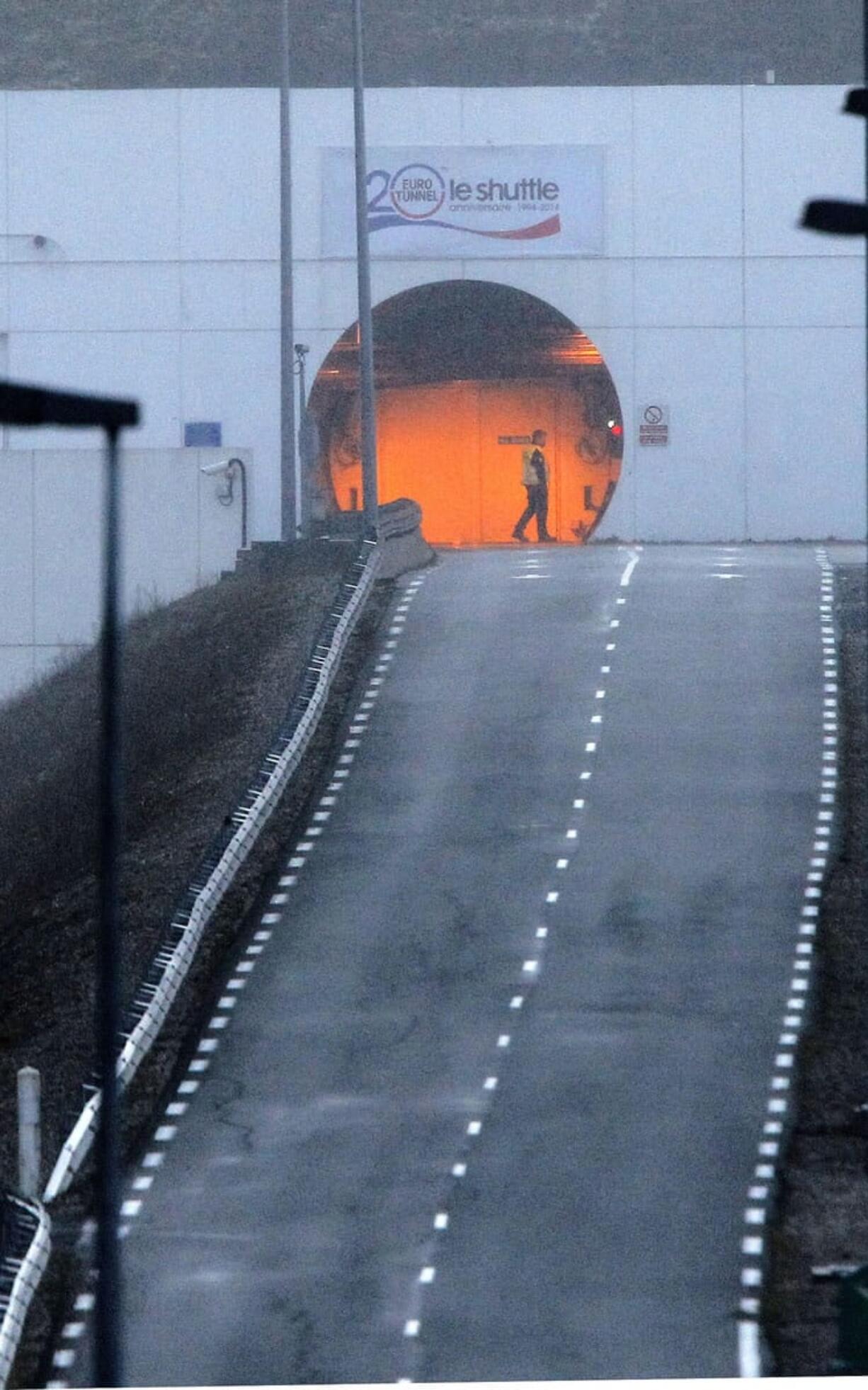 A railway worker walks Saturday, Jan. 17, 2015, past the entrance to the Channel Tunnel in Coquelles, France, near Calais. A fire in a truck that was being transported through the tunnel triggered an alarm, which led to suspension of all passenger and freight rail services between Britain and France on Saturday, police said. No injuries were reported.