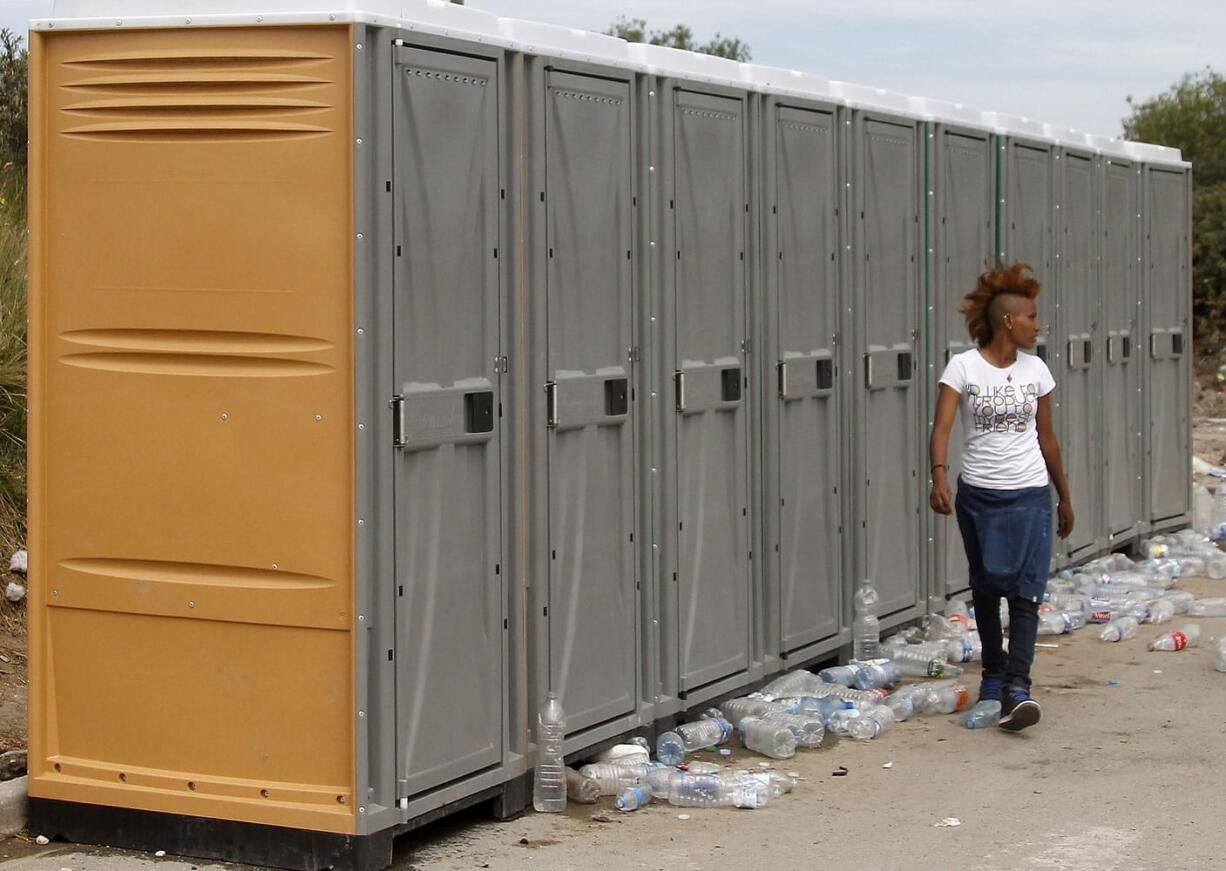 A migrant walks past a toilet station in a makeshift camp known as the &quot;jungle&quot;, in Calais, northern France, on Thursday